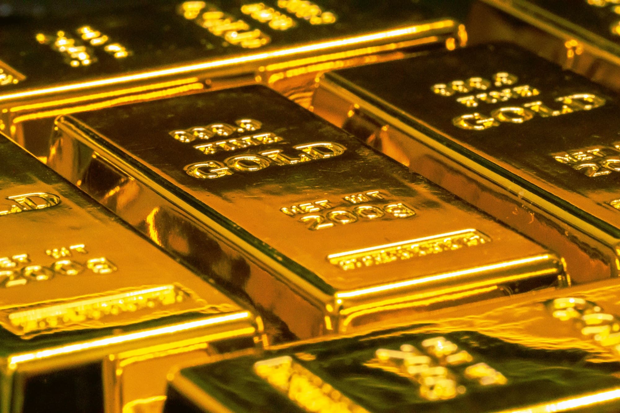 Rows of gold bars stamped 999.9 fine gold, glowing under warm light